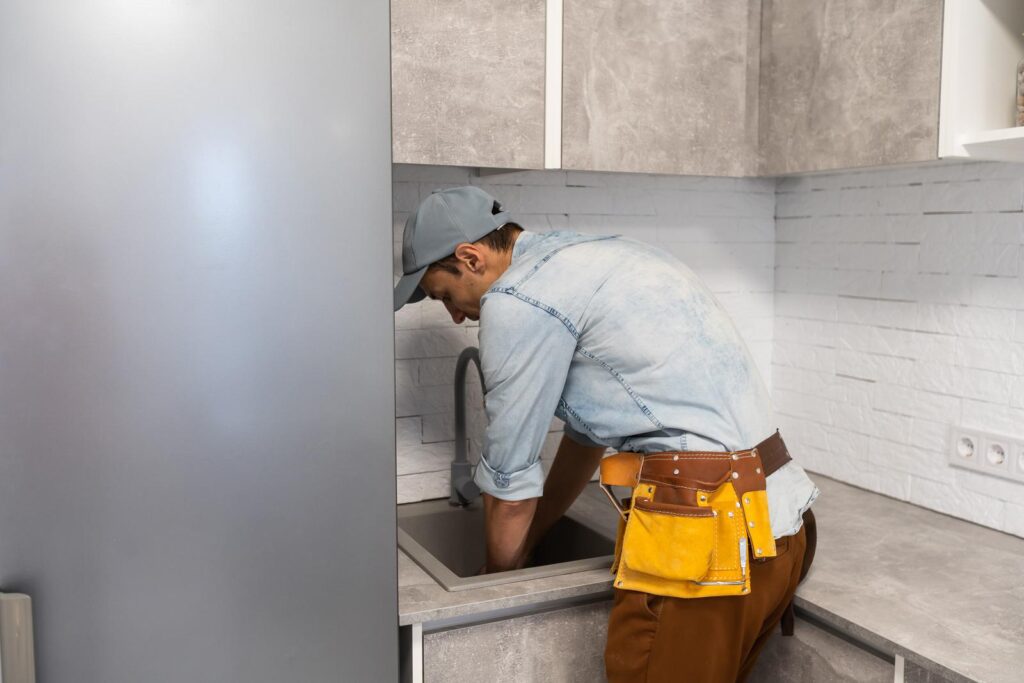 plumber repairing faucet in kitchen