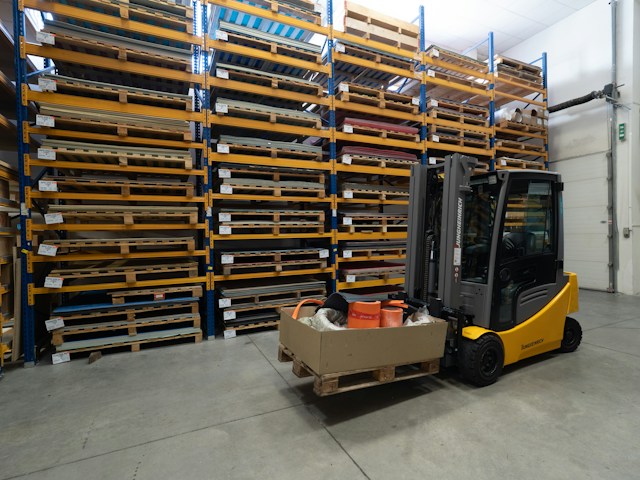 A small forklift lifting a pallet, in a warehouse