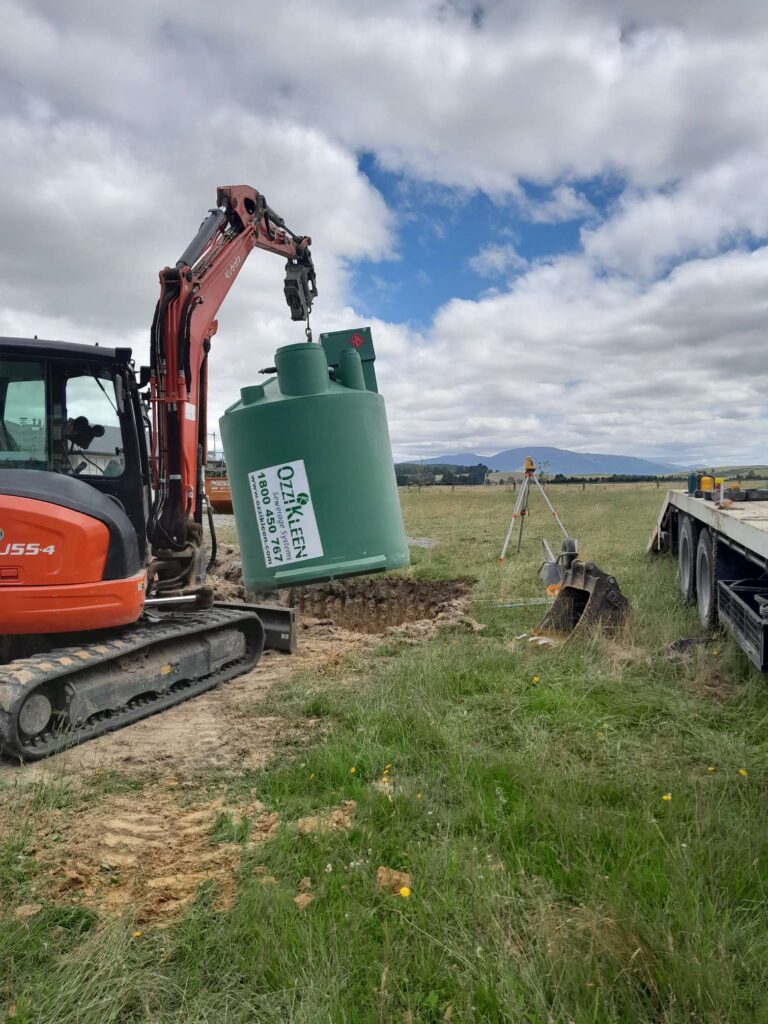 digger carrying plastic septic tank