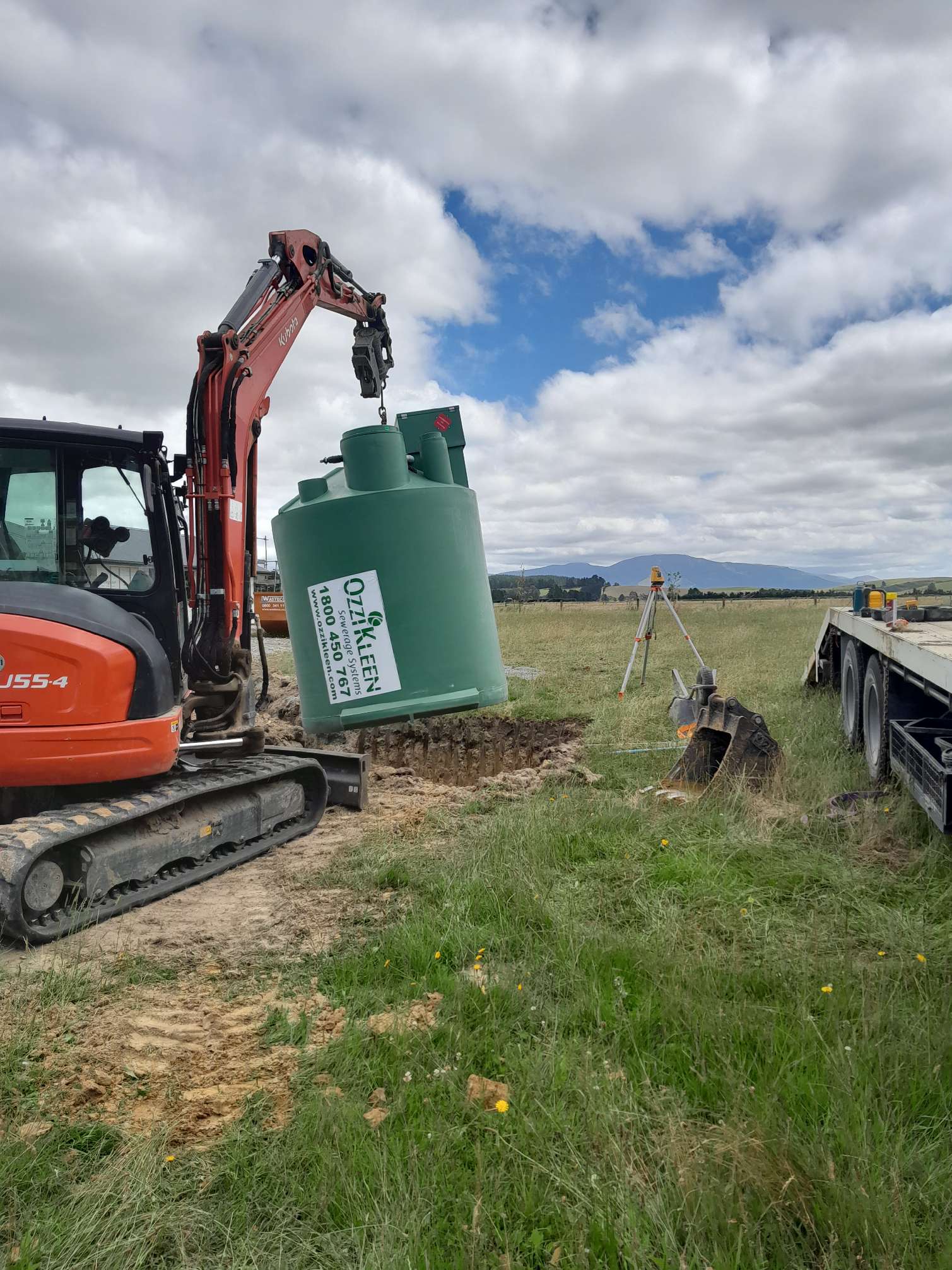 digger carrying plastic septic tank