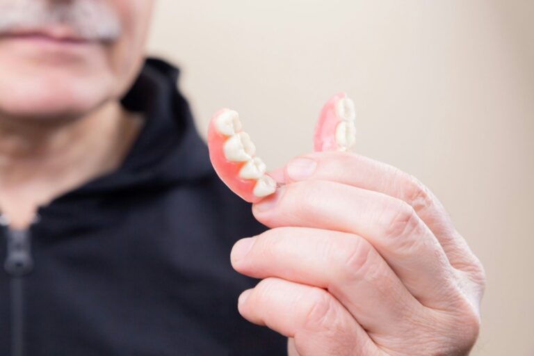An older man holding broken dentures, highlighting the need for urgent denture repairs in Te Awamutu.